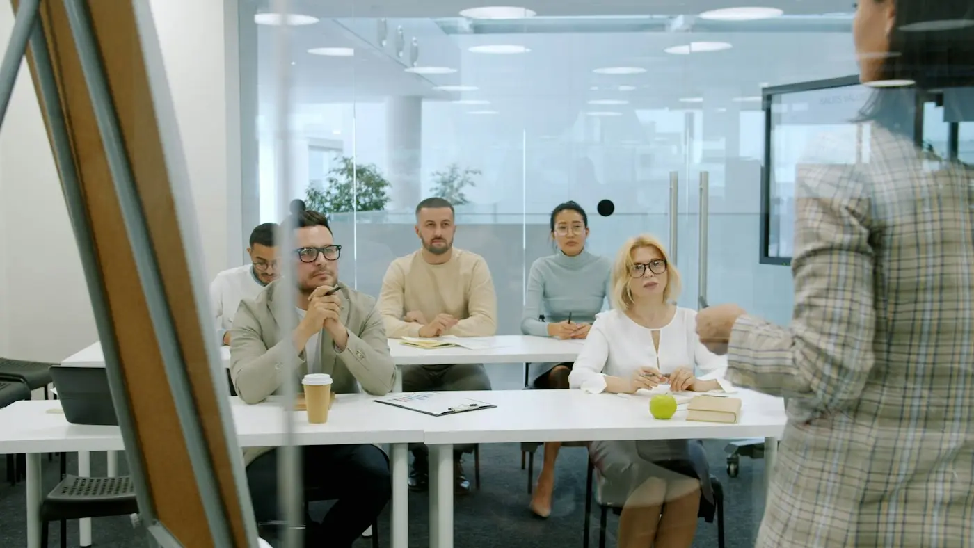 Un groupe de stagiaires attentifs autour des tables d'une salle de formation