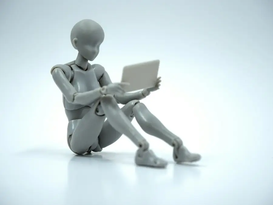 Figurine articulée assise avec un ordinateur portable